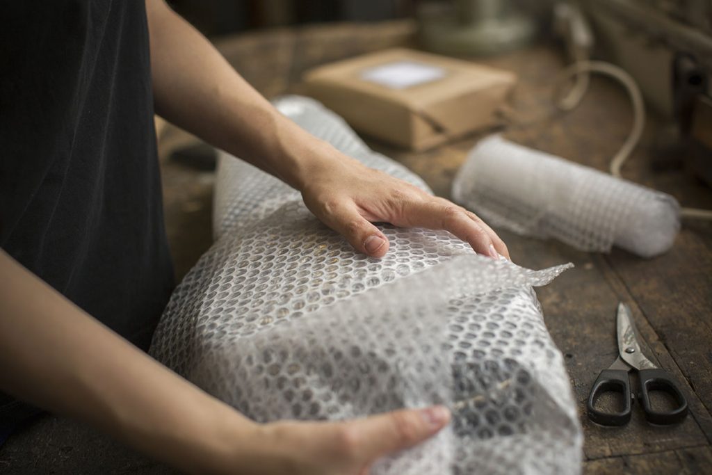 Mulher embrulhando itens com plástico bolha