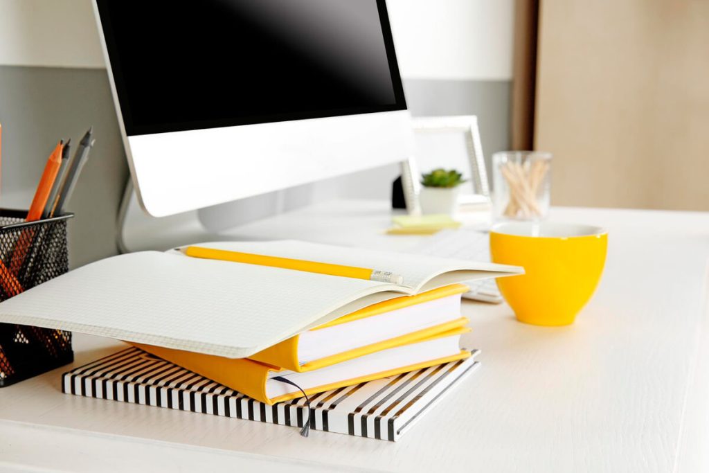Escrivaninha com livros, cadernos e computador