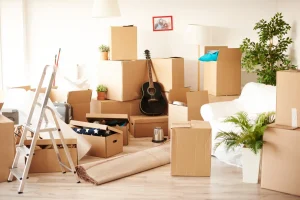 Quarto elegante parcialmente ocupado por caixas, móveis e objetos organizados de forma acumulada